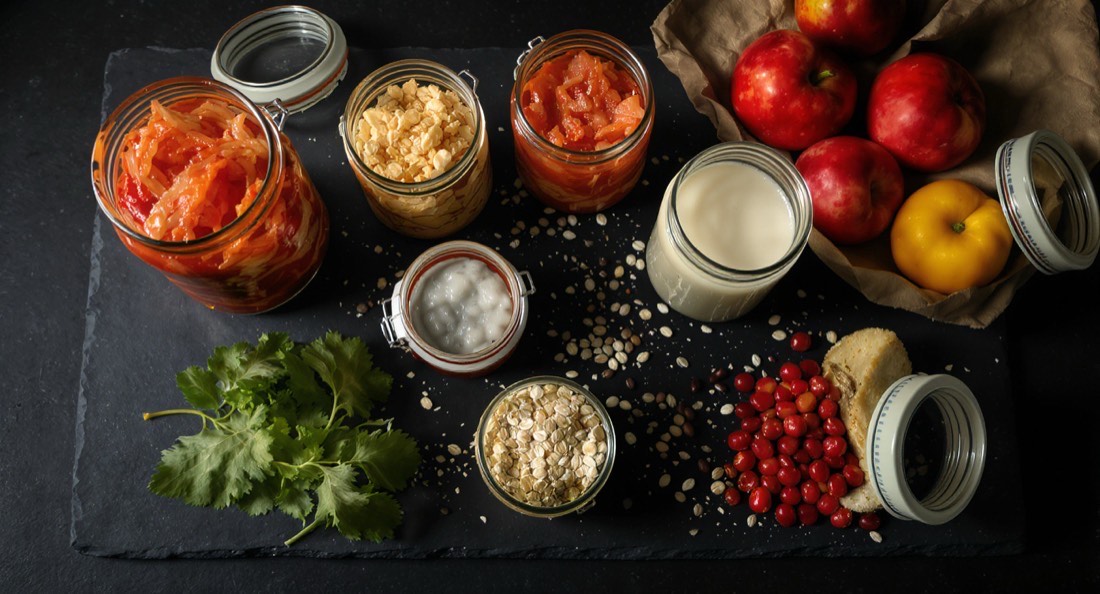 Jars of sauerkraut and kimchi with kefir, beans and oats on dark slate