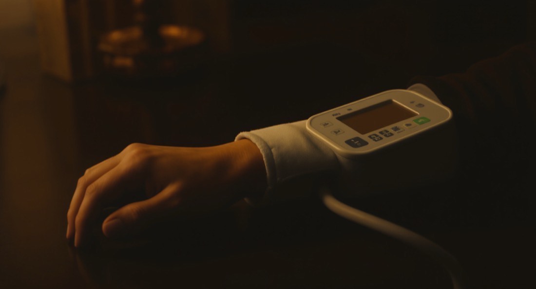 A home blood pressure cuff on a forearm resting on a dark table