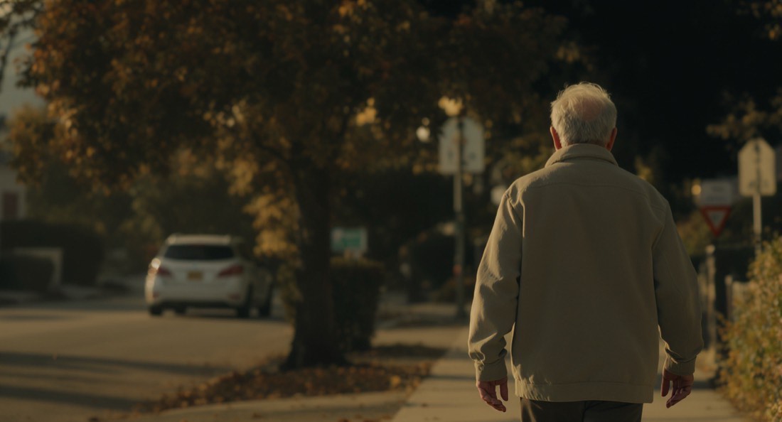 A person in their fifties walking outdoors after a meal in late afternoon light